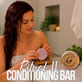 Grace and Glade - Ritual II Cleansing Conditioning Bar - Image shows  woman with wet red color treated hair holding a ritual two conditioning bar, placing it on a wood soap rack for drying.